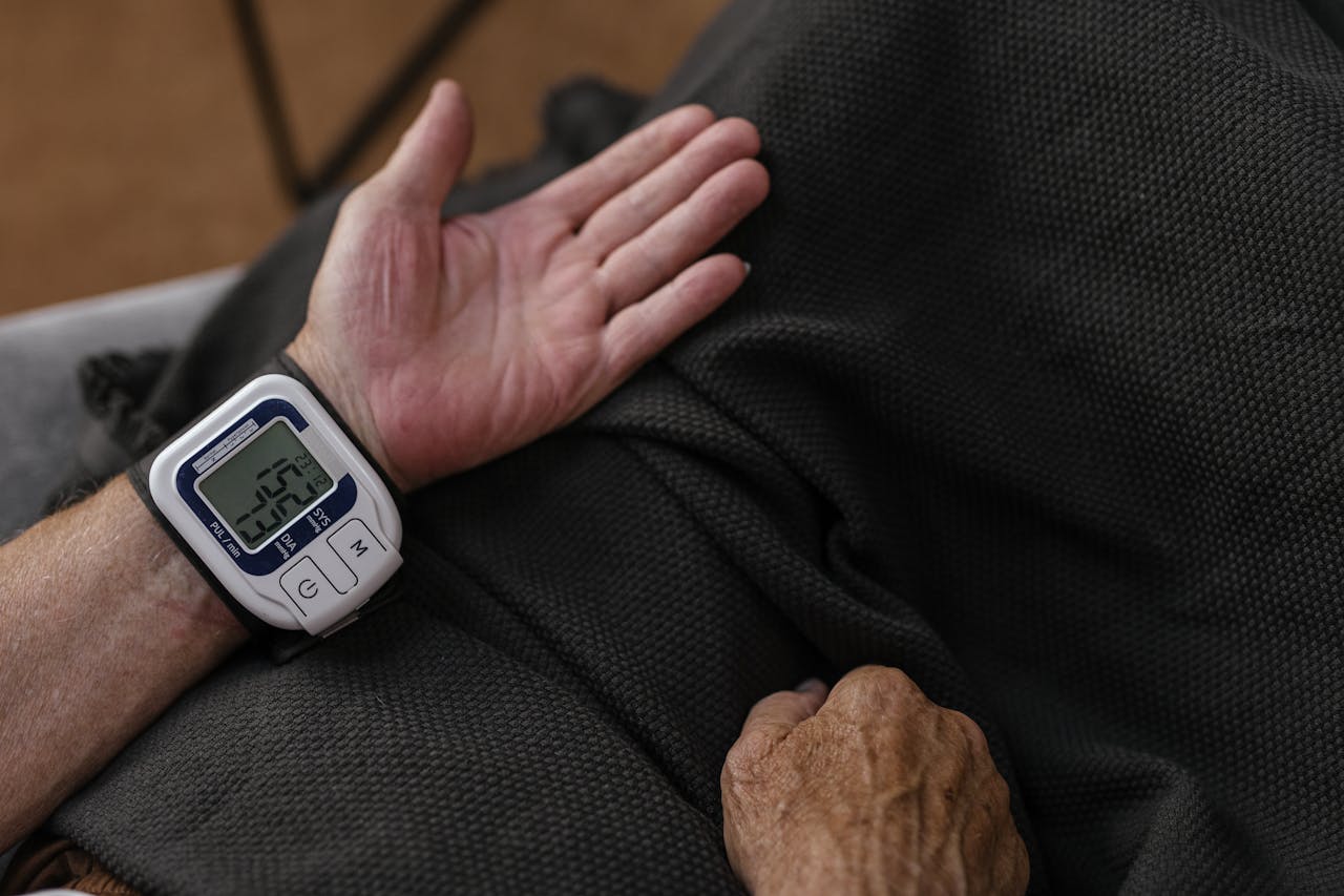 who-we-are A senior adult using a wrist blood pressure monitor at home, focusing on health management.